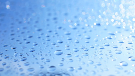 Watter drops on window with blue sky and sun lightの写真素材