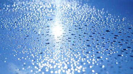 Watter drops on window with blue sky and sun lightの写真素材