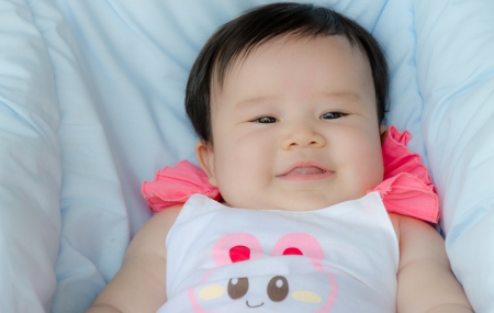 a pretty asian baby girl smiling happilyの写真素材
