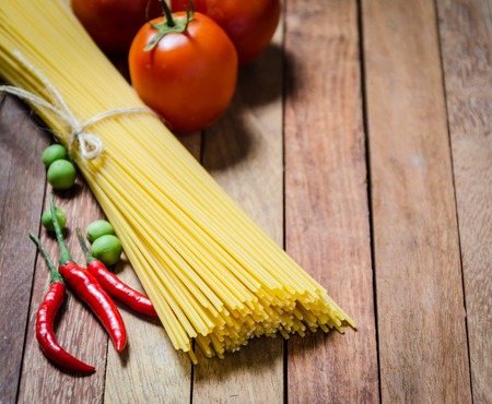 Spaghetti and tomatoes with chilli on wooden backgroundの写真素材