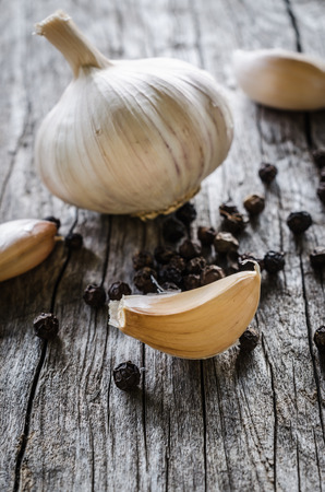 Garlic bulb and cloves with pepper on wooden backgroundの写真素材