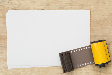 Blank paper with photo film in cartridge  on wooden table.の写真素材