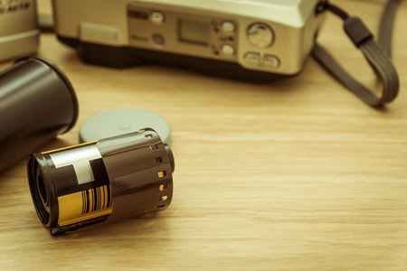 photo film in cartridge and film camera on wooden table.の写真素材