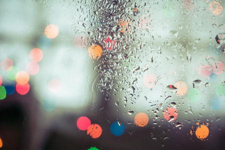 drops on window with light bokeh, rainy season abstract background.の写真素材