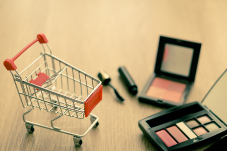 Shopping cart with cosmetics on wood background.の写真素材