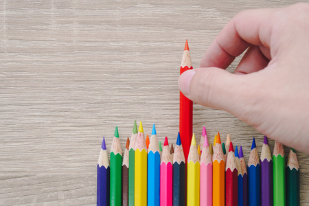 Hand choosing a colored pencil on wooden background.の写真素材