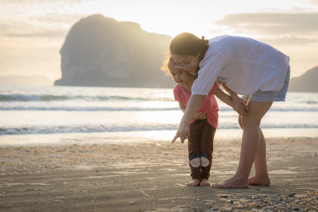Happy mother and young daughter on the beach at sunset.の写真素材
