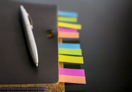 Notebook with colorful sticky bookmarks on black background-close up.の写真素材