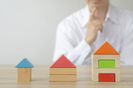 Real estate concept - man making  decision to choose the house behind home  model.の写真素材