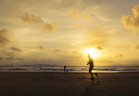 Silhouette of man running on the sunset beach.の写真素材