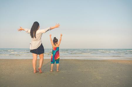Happy mother and young daughter on the beach at sunset.の写真素材