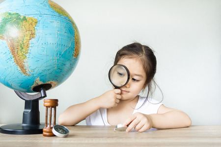 A pretty asian girl using magnifying glass. Learning, education concept.の写真素材