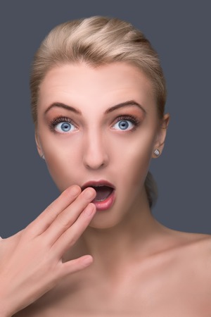 Surprised beautiful girl. face closeup with handの写真素材