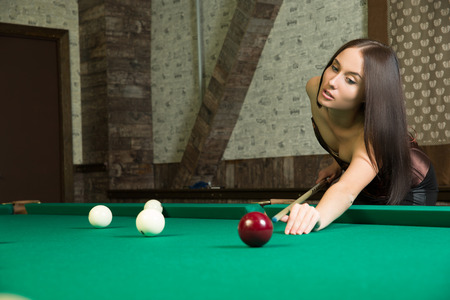 sexy girl in corset plays billiards.