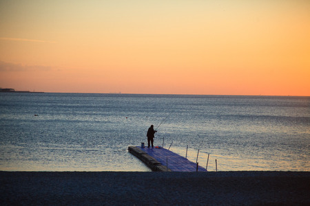 Silhouette sitting young woman on sunsetの写真素材
