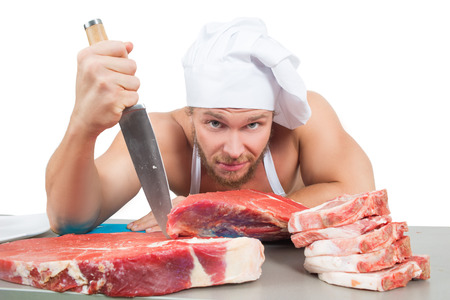 male bodybuilder chef cuts raw meat.の写真素材