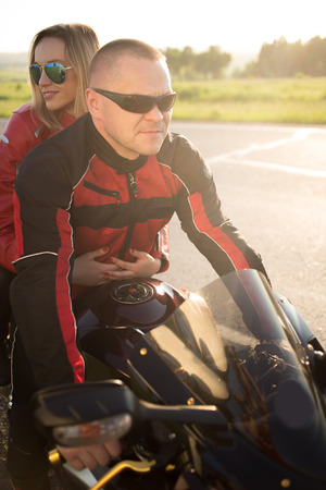biker man and woman sitting on a motorcycle.