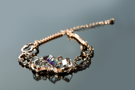 golden bracelet with precious stones on grey background