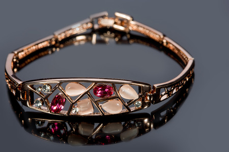 golden bracelet with precious stones on grey background