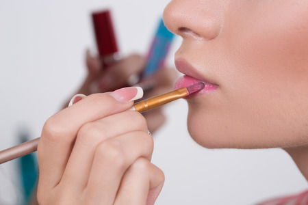 Makeup artist applies lipstick. Beautiful woman face. Perfect makeup