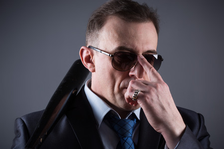 male gangster with baseball bat on a gray backgroundの写真素材