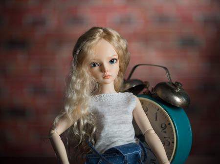 lovely doll on the background of the old clock.の写真素材