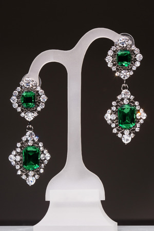 earrings with green stones on a stand on the black backgroundの写真素材