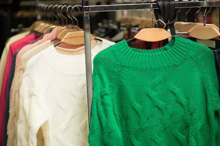 Close up of sweaters, sweatshirts on retail shop rack. Store interior.