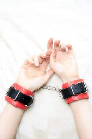 female hands in leather handcuffs. on the background sheet. sex toys. passionの写真素材