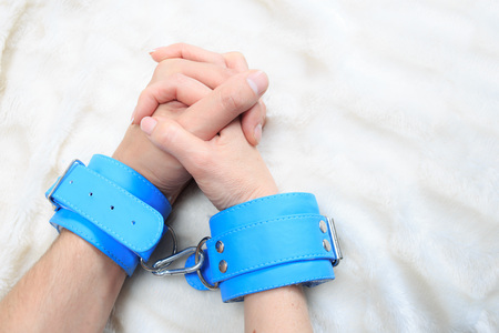 Male and female hands in handcuffs. couple in bed. sex Toysの写真素材