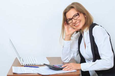 bored female office worker sits at her desk and look at computer screenの写真素材