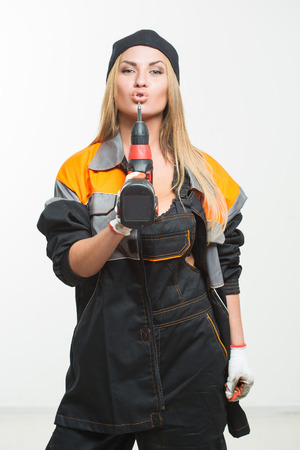 Young sexy female holding a cordless screwdriver. white isolated backgroundの写真素材