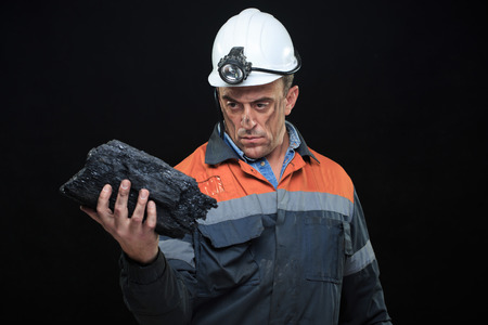A coalminer holds out a large chunk of energy rich coal in a dark coalmine.の写真素材
