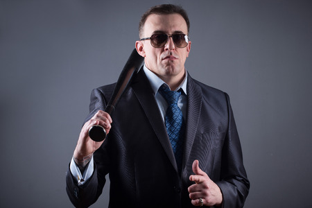 male gangster with baseball bat on a gray backgroundの写真素材