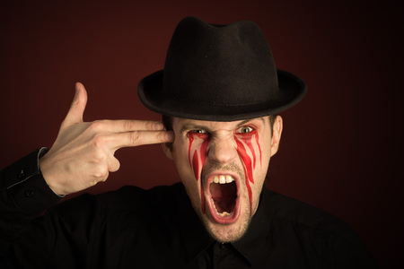 portrait of a man with bloody tears on burgundy background