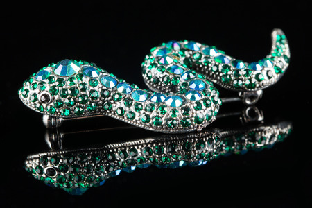 brooch in the form of a snake. green stones. on black backgroundの写真素材