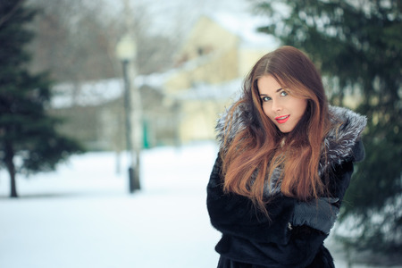 beautiful smiling girl on a background of trees. Winter portrait. coat with a hoodの写真素材