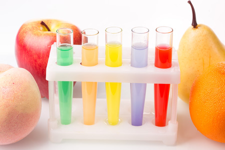 Fruit close chemical test tubes. Genetic Engineering. pesticides in foods. White background.の写真素材