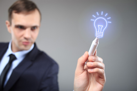 Businessman draws a burning lamp. concept ideaの写真素材