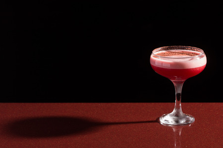 A glass with the red citrus cocktail. foam. sprinkle with spices