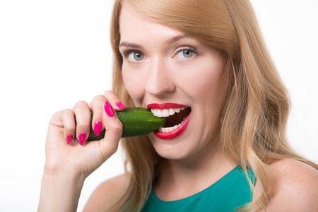Happy young woman eating cucumber. A close-up of beautiful girl eating cucumber.の写真素材