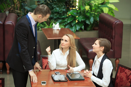Waitress taking order from businessmen in cafe smiling laptop workの写真素材