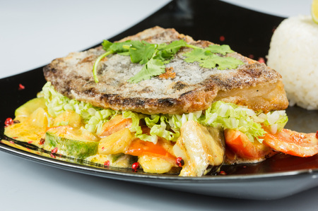 Tasty fish with vegetables and lemon on table