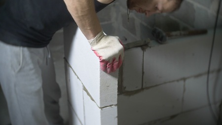 a construction site, a builder puts a wall of gas blocks