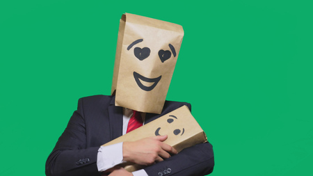 concept of emotions, gestures. a man with a package on his head, with a painted emoticon, smile, enamored eyes. plays with the child painted on the boxの写真素材