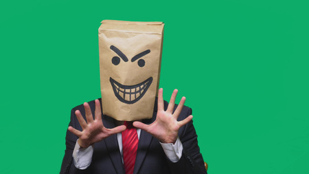concept of emotion, gestures. a man with a package on his head, with a painted smiley angry, sly, gloating.の写真素材