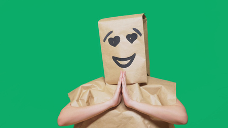 concept of emotions, gestures. a man with paper bags on his head, with a painted emoticon, smile, joy, love eyesの写真素材