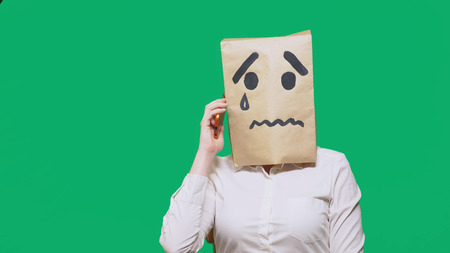 concept of emotion, gestures. a man with a package on his head, with a painted smiley crying, sad, talking on the phone.の写真素材