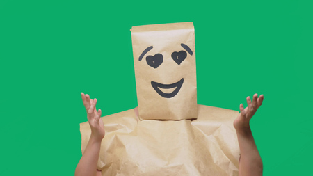 concept of emotions, gestures. a man with paper bags on his head, with a painted emoticon, smile, joy, love eyesの写真素材