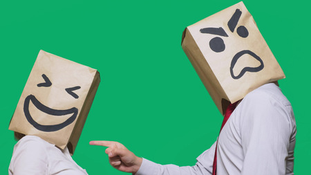 The concept of emotions and gestures. Two people in paper bags with smiles. Aggressive smiley swears. Second laughs at him.の写真素材